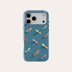 Puede incluir: Una funda de teléfono azul con un diseño de tablas de surf de colores sobre un mar azul. Las tablas de surf son de varios colores, incluyendo rojo, amarillo y rosa. La funda tiene un acabado brillante y un recorte para la cámara.