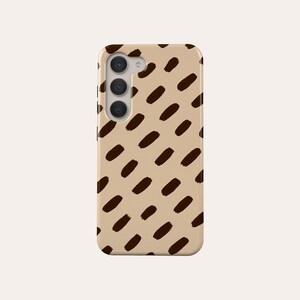 May include: A phone case with a tan background and a repeating pattern of dark brown, oval-shaped brushstrokes. The case has a camera module with three lenses.
