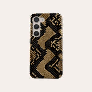 Op de afbeelding: Een zwarte en gouden telefoonhoes met een slangenhuidpatroon.