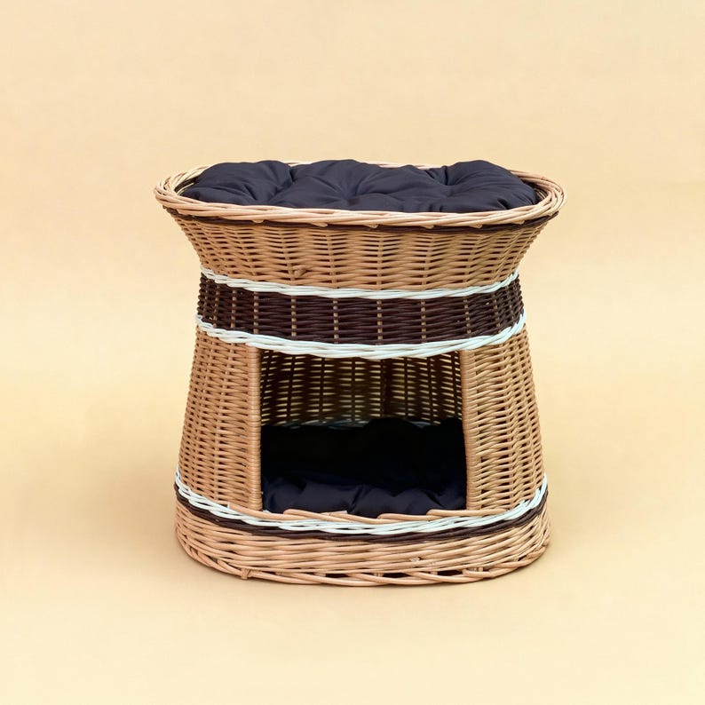 May include: A woven wicker pet bed with a dark blue cushion. The bed has a cylindrical shape with a rounded top and a rectangular opening. The bed is made of light brown wicker with dark brown and white accents.