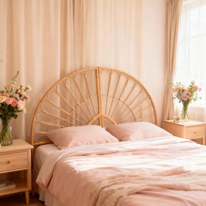 May include: A semi-circular rattan headboard with a fan-like pattern of vertical slats. The headboard is positioned behind a bed dressed in light pink bedding, flanked by two light-colored wooden nightstands with floral arrangements.
