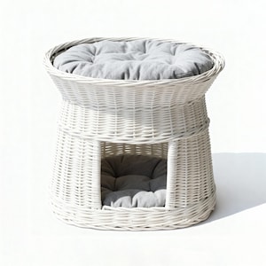May include: White wicker pet bed with a round top and a lower enclosed area. The bed has a gray cushion on the top and inside the enclosed space. The woven design gives the bed a natural, airy look.