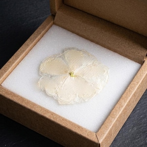 May include: A white ceramic mug with a black handle and the text "But First, Coffee" in a bold, black font. The mug is set against a blurred background, suggesting a cozy setting.