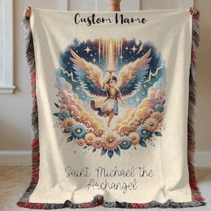 May include: Cream-colored throw blanket with a detailed illustration of Saint Michael the Archangel. The design features an angel with large wings, surrounded by flowers and clouds. The text "Custom Name" and "Saint Michael the Archangel" are written on the blanket.