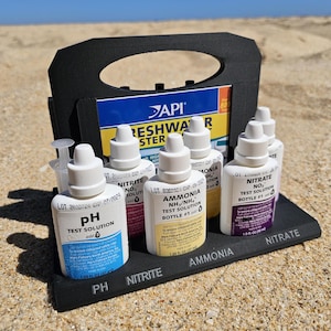 May include: A black plastic carrying case with six clear plastic bottles containing API Freshwater Master Test Kit solutions for pH, Nitrite, Ammonia, and Nitrate. The bottles are labelled with the test solution name and the lot number.
