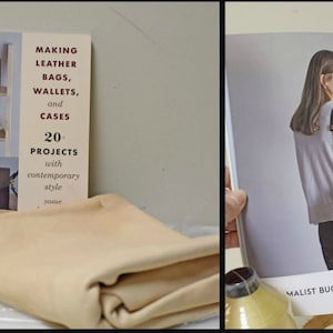 May include: A book titled "Making Leather Bags, Wallets, and Cases: 20 Projects with Contemporary Style" with a tan leather piece folded on top of it. There is a spool of tan thread and a spool of yellow thread next to the book.