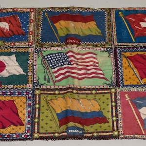 Könnte beinhalten: Ein Vintage-Stoff-Patchwork mit neun Quadraten, die jeweils die Flagge eines anderen Landes zeigen. Die Flaggen umfassen Siam, Bolivien, die Schweiz, Japan, die USA, Tunesien, England, Ecuador und 'J'stonien'.