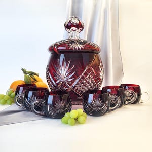 Könnte beinhalten: Ein Set aus sechs roten Kristall-Punschgläsern und einer großen roten Kristall-Punschschale mit Deckel. Die Schale und die Gläser haben ein geschliffenes Glasdesign.