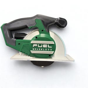 Puede incluir: Un modelo de sierra circular en verde y negro con un mango texturizado y una placa base plateada. El lateral de la herramienta muestra el texto en relieve FUEL BRUSHLESS en letras blancas sobre una carcasa circular verde.