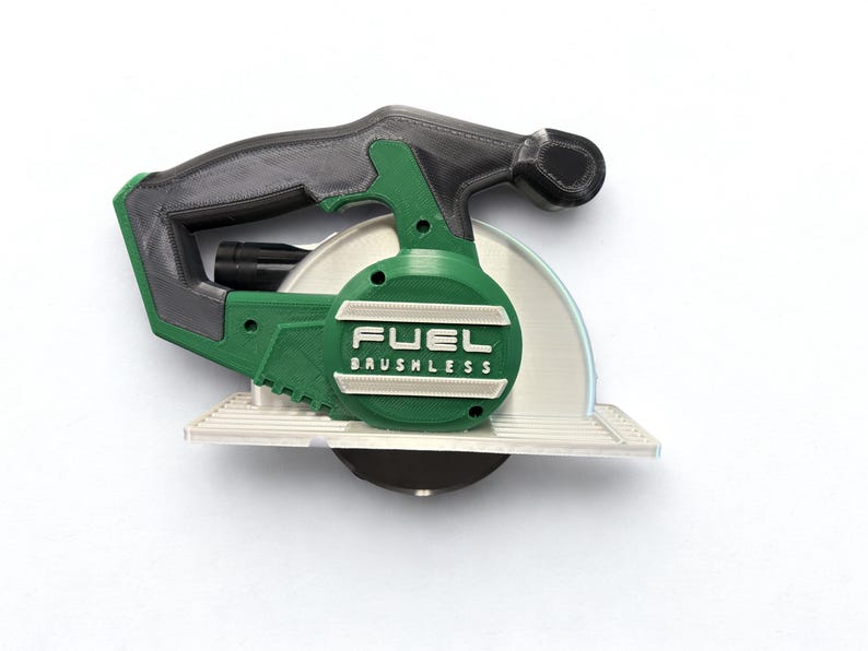 Puede incluir: Un modelo de sierra circular en verde y negro con un mango texturizado y una placa base plateada. El lateral de la herramienta muestra el texto en relieve FUEL BRUSHLESS en letras blancas sobre una carcasa circular verde.