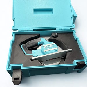 Puede incluir: Una sierra circular de color azul claro con hoja plateada y mango negro, que presenta el texto FUEL BRUSHLESS en la carcasa del motor. La herramienta se guarda en un inserto de espuma negra a medida dentro de un malet&iacute;n de pl&aacute;stico.
