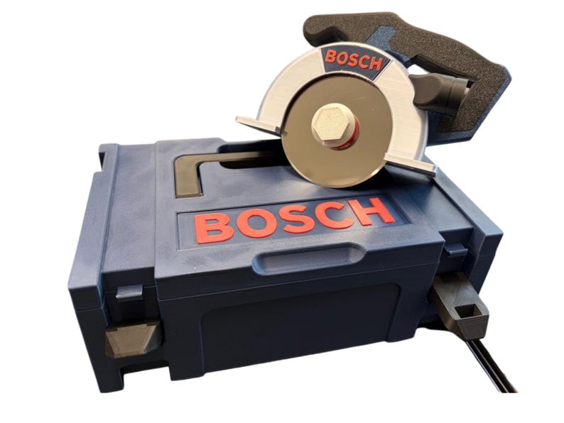 Puede incluir: Una sierra circular Bosch de color azul con una hoja de metal plateado y un mango negro, apoyada sobre un malet&iacute;n de transporte de pl&aacute;stico Bosch azul a juego. El nombre de la marca Bosch aparece en letras rojas en la herramienta y el estuche.