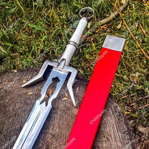 May include: A silver and white sword with a red sheath rests on a wooden surface. The sword features a detailed hilt and a decorative blade. The sheath is a vibrant red with a silver cap, creating a striking contrast.