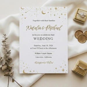 May include: A wedding invitation with gold celestial accents, featuring the names "Natalia & Michael." The invitation includes the wedding date, time, and location. Two ring boxes and three gold wax seals are also present, along with dried foliage.