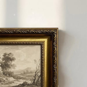 Puede incluir: Una impresión enmarcada de un paisaje con un marco dorado ornamentado. La obra de arte es un dibujo en blanco y negro de una escena rural con árboles, colinas y un camino. El marco tiene un diseño decorativo detallado.