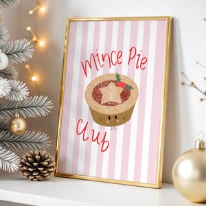 May include: A framed print with a gold border. The print has a pink and white striped background and features the words "Mince Pie Club" in red script. A cartoon mince pie with a star topping and holly is also shown. Christmas decorations are in the background.