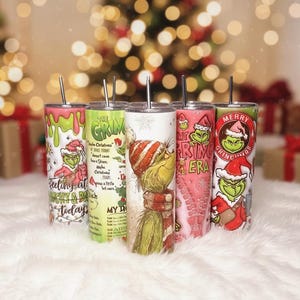 May include: Six stainless steel tumblers with Grinch-themed designs. Each tumbler has a different design, including the Grinch in a Santa hat, text that says "Feeling at Naughty & Rich Today", and other festive graphics.