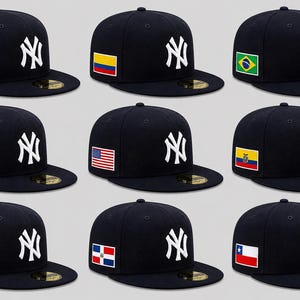 May include: Nine navy blue baseball caps with the New York Yankees logo in white. Each cap features a different flag patch on the side, including Mexico, Colombia, Brazil, Argentina, the United States, Ecuador, Puerto Rico, Dominican Republic, and Chile.