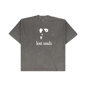 May include: A gray t-shirt with a white graphic of a face and the words "lost souls" printed below. The shirt has short sleeves and a crew neck. The fabric appears to be pre-shrunk.