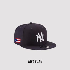 Può includere: Cappellino da baseball blu navy con visiera piatta, con il logo bianco dei New York Yankees. La bandiera portoricana è ricamata sul lato. Il testo "ANY FLAG" è visualizzato in grassetto, in nero, in basso.