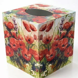 May include: A square tissue box featuring a vibrant floral design. The box is covered with a watercolor-style print of red poppies, green foliage, and other wildflowers. The top has a central oval opening for tissue dispensing.