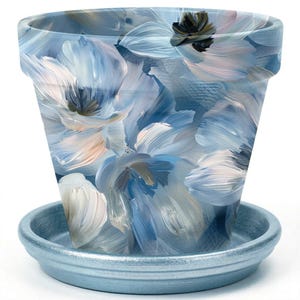 May include: A tapered flower pot with a matching saucer, featuring a painted design of large, abstract blue, white, and soft pink floral petals with visible brushstrokes. The saucer has a solid, metallic light blue finish and a raised rim.