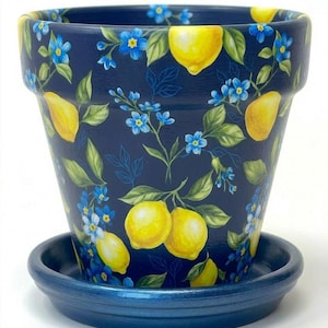 May include: A dark navy blue plant pot with a matching saucer, featuring a repeating pattern of bright yellow lemons, green leaves, and small light blue flowers. The cylindrical pot has a wide rim and a smooth finish, showcasing a botanical design.