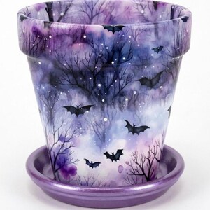 May include: A tapered ceramic plant pot and matching saucer featuring a watercolor-style print of a dark forest with bare trees, scattered white dots, and black silhouettes of flying bats against a gradient of purple, blue, and white hues.