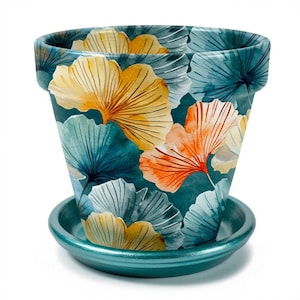 May include: A tapered ceramic plant pot with a matching saucer, featuring a dark teal background decorated with a repeating pattern of ginkgo leaves in shades of golden yellow, soft orange, and muted blue, with a smooth, glossy finish throughout.