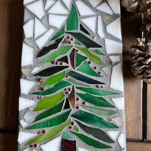May include: A mosaic Christmas tree made of green, white, and brown glass tiles. The tree is decorated with small red glass beads.