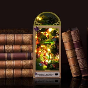 May include: A miniature illuminated diorama of a forest scene with a house, trees, and mushrooms. The diorama is encased in a wooden frame with the text "FIREFLY FOREST" and is surrounded by antique books.