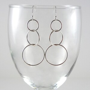 May include: Silver earrings with three interlocking circles of different sizes.