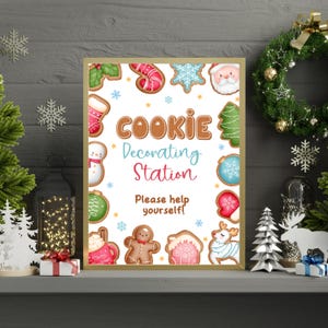 May include: A framed sign with the words "Cookie Decorating Station" and the phrase "Please help yourself!" surrounded by festive cookie illustrations. The sign is in a gold frame and is set on a mantel.