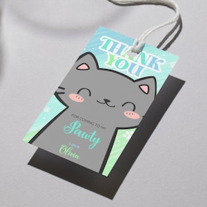 Può includere: Un'etichetta regalo rettangolare con un design a forma di gatto dei cartoni animati. L'etichetta presenta le parole "THANK YOU" in blu e verde e il testo "FOR COMING TO MY Sawty Love Olivia". Il gatto è grigio con accenti rosa e uno spago bianco.