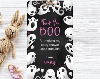 May include: A Halloween-themed gift tag with a black background and white ghost illustrations. The tag reads "Thank You BOO" in pink, with additional text for a baby shower. A brown string and bow are at the top.