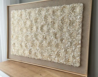 May include: A large framed wall art piece featuring a beige background with a textured pattern of white shell flowers.