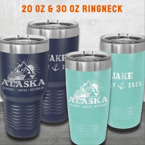 K&ouml;nnte beinhalten: Vier Edelstahl-Ringneck-Becher, zwei marineblau und zwei t&uuml;rkis. Jeder Becher hat einen silbernen Deckel und zeigt das Wort "Alaska" mit einem Berg-, Sonnen- und Kreuzfahrtschiff-Design. Ein t&uuml;rkisfarbener Becher tr&auml;gt den Namen "Jake" und das Jahr "2025".