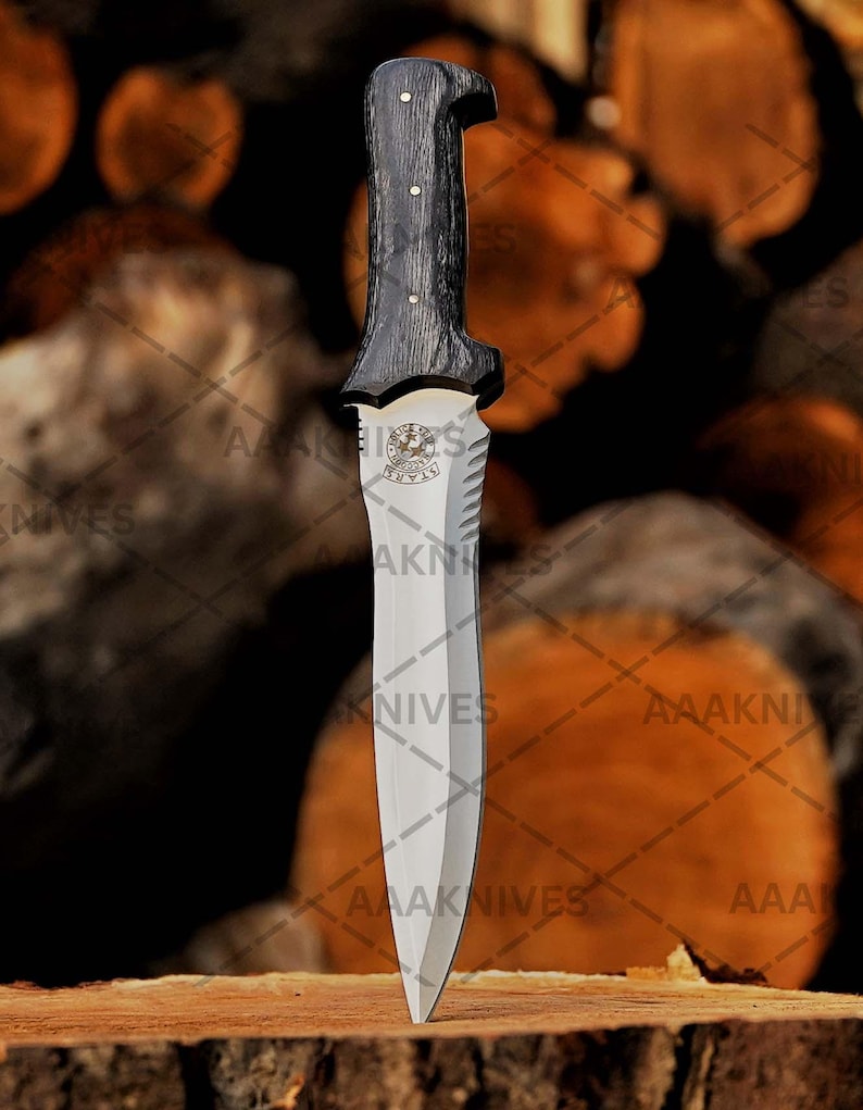 May include: A dagger with a dark wooden handle and a silver blade. The handle has a unique shape and is attached to a silver guard with a decorative emblem. The blade is sharp and pointed. The text "AAAKNIVES" is visible.