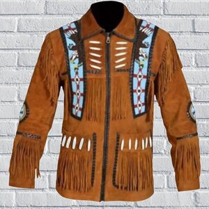 Könnte beinhalten: Braune Wildlederjacke mit Fransen und dekorativen Perlen. Die Jacke hat einen Reißverschluss vorne, einen Kragen und detaillierte Muster in Blau, Weiß und Schwarz. Die Ärmel haben runde Aufnäher mit Designs.