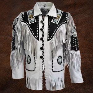 Könnte beinhalten: Weiße Lederjacke mit schwarzen Akzenten, Fransen und dekorativen Nähten. Die Jacke hat eine Knopfleiste, einen Kragen und Muster auf den Schultern und Taschen. Die Ärmel sind lang und die Jacke hat ein Design im Western-Stil.
