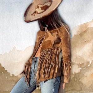 Könnte beinhalten: Braune Wildlederjacke mit Fransen und Sternen, kombiniert mit einem Cowboyhut und blauen Jeans. Die Jacke hat eine Schnürung vorne und lange Fransen an Saum und Ärmeln. Der Hut ist beige mit einem Kuhfellmuster.