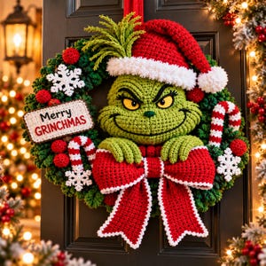 May include: A crocheted wreath featuring a green character with yellow eyes wearing a red and white Santa hat. The wreath is decorated with red yarn balls, white snowflakes, red and white candy canes, and a large red bow. A sign reads Merry GRINCHMAS.