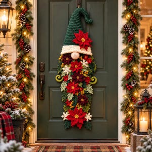 Könnte beinhalten: Ein gehäkelter Wichtel als Türschmuck mit einer hohen, dunkelgrünen Zipfelmütze mit weißem Rand, einer runden beigen Nase und einem langen Bart, der mit roten und dunkelroten Weihnachtssternen, grünen Blättern, gelben Beeren und weißen Schneeflocken verziert ist.