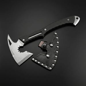 Puede incluir: Un hacha t&aacute;ctica con mango negro y hoja plateada, mostrada con su funda de cuero negro. El cabezal del hacha tiene un dise&ntilde;o &uacute;nico con una hoja curva y una secci&oacute;n dentada. Longitud total aproximada de 30 cm.