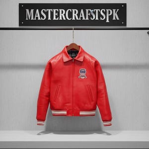 May include: A vibrant red leather jacket with a classic collar and a patch on the chest. The jacket has white and red striped cuffs and a white stripe at the bottom. The sign above reads "MASTERCRATSPSK".