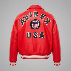 May include: Red leather jacket with white and red striped cuffs and hem. The back features the text "AVIREX" above "USA" and a circular patch with a flag design. A classic bomber jacket style.