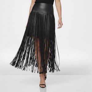 May include: A black leather skirt with long fringe detailing. The skirt has a high waist and falls to the ankles. The fringe moves dynamically, creating a flowing effect. The model is wearing black sandals.
