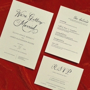 May include: Wedding stationery set on a red background. The main card says "We're Getting Married" with names and date. Other cards provide ceremony details and RSVP information.