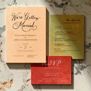 May include: Wedding invitation suite with three cards. The main card reads "We're Getting Married" with the couple's names and date. A second card details the ceremony, reception, and accommodations. The RSVP card is red with dinner selection options.