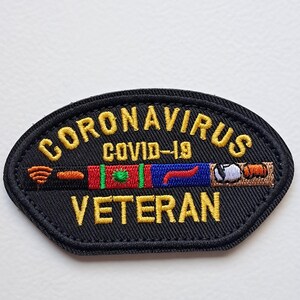 Può includere: Toppa ricamata nera con le parole "CORONAVIRUS COVID-19 VETERAN" in giallo. La toppa presenta un design colorato con sezioni rosse, verdi, blu e marroni. La toppa è di forma ovale.